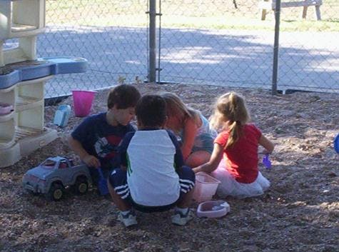 Four children playing in sand with toys