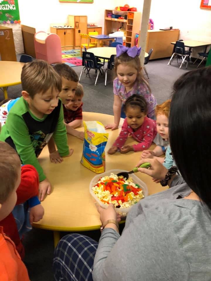 Children gathered around a table watching a person serve food