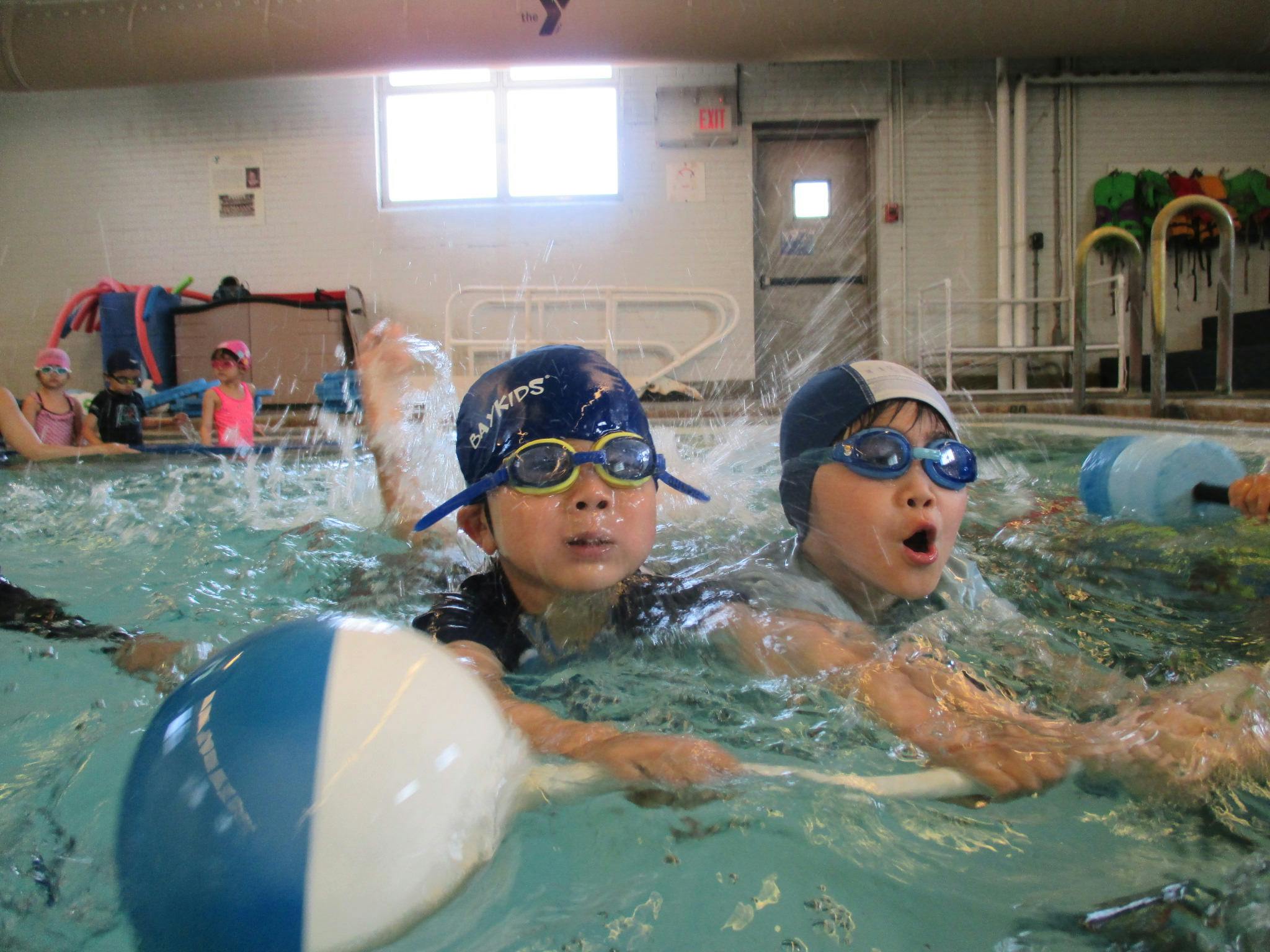 Two children in swim caps and goggles in a swimming pool