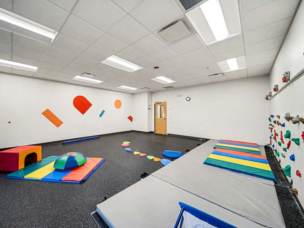 Playroom with colorful mats, soft play equipment, and a climbing wall