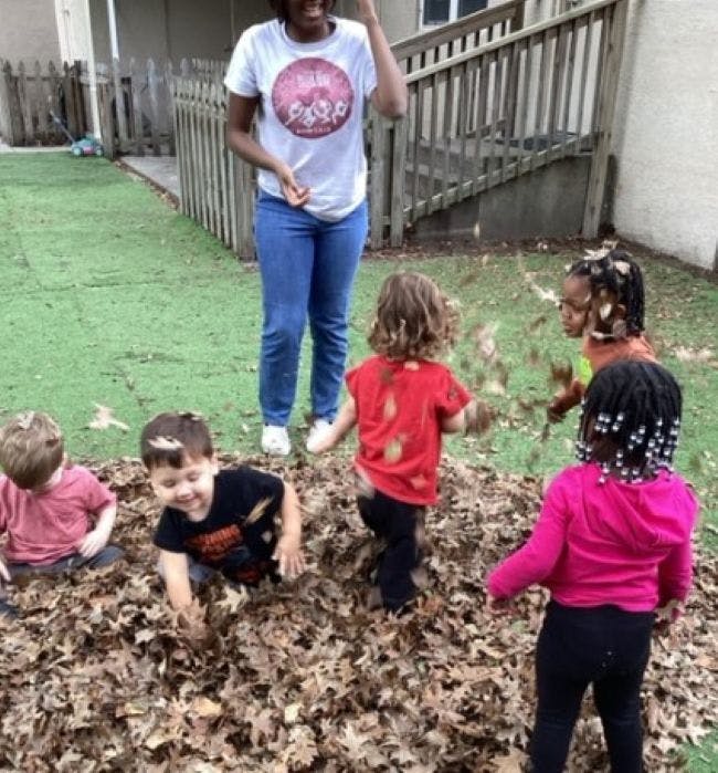 Person watching children playing in a pile of leaves