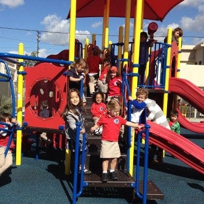 Children playing on a red and yellow playground structure