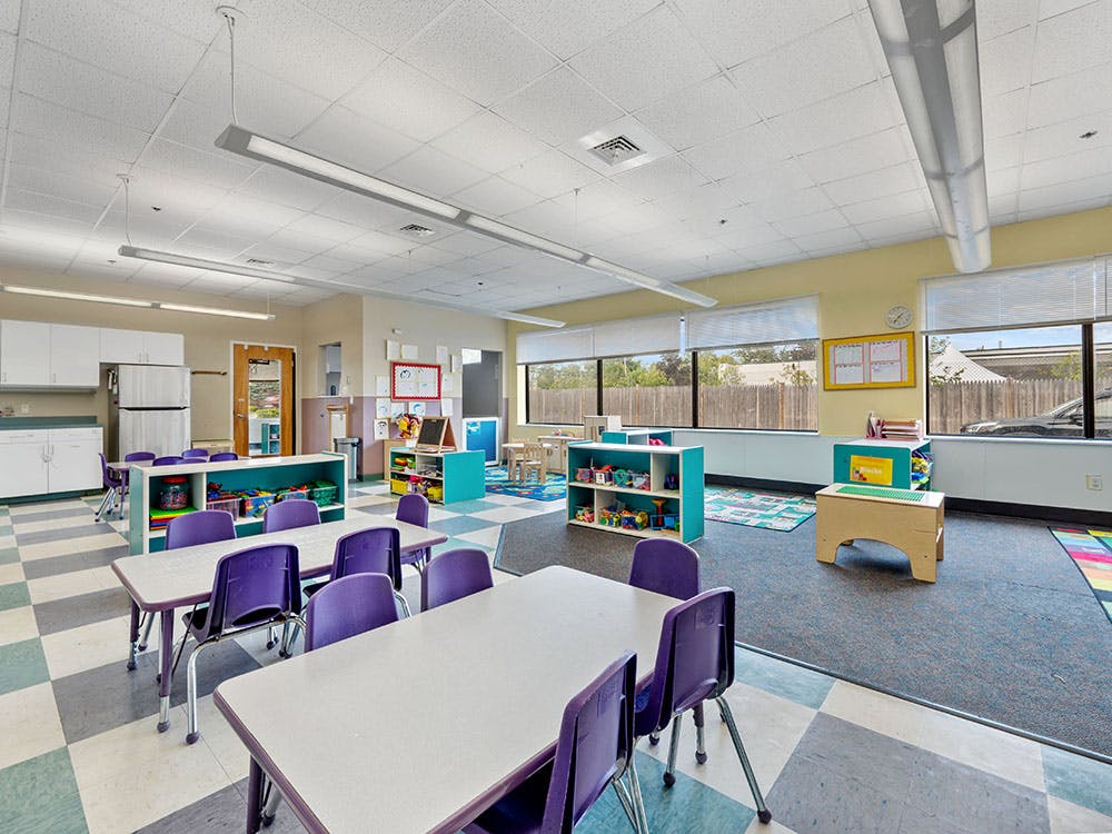 Empty colorful preschool classroom with small tables and chairs