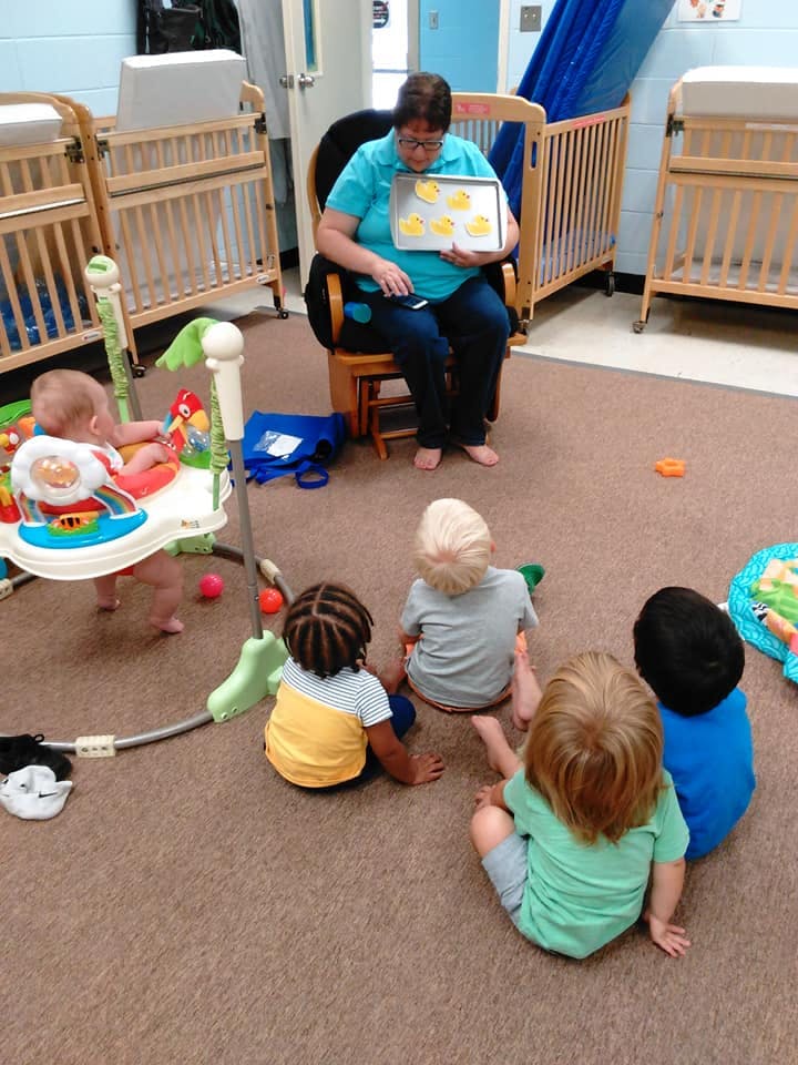 Person holding a tray of star-shaped objects for children sitting on the floor