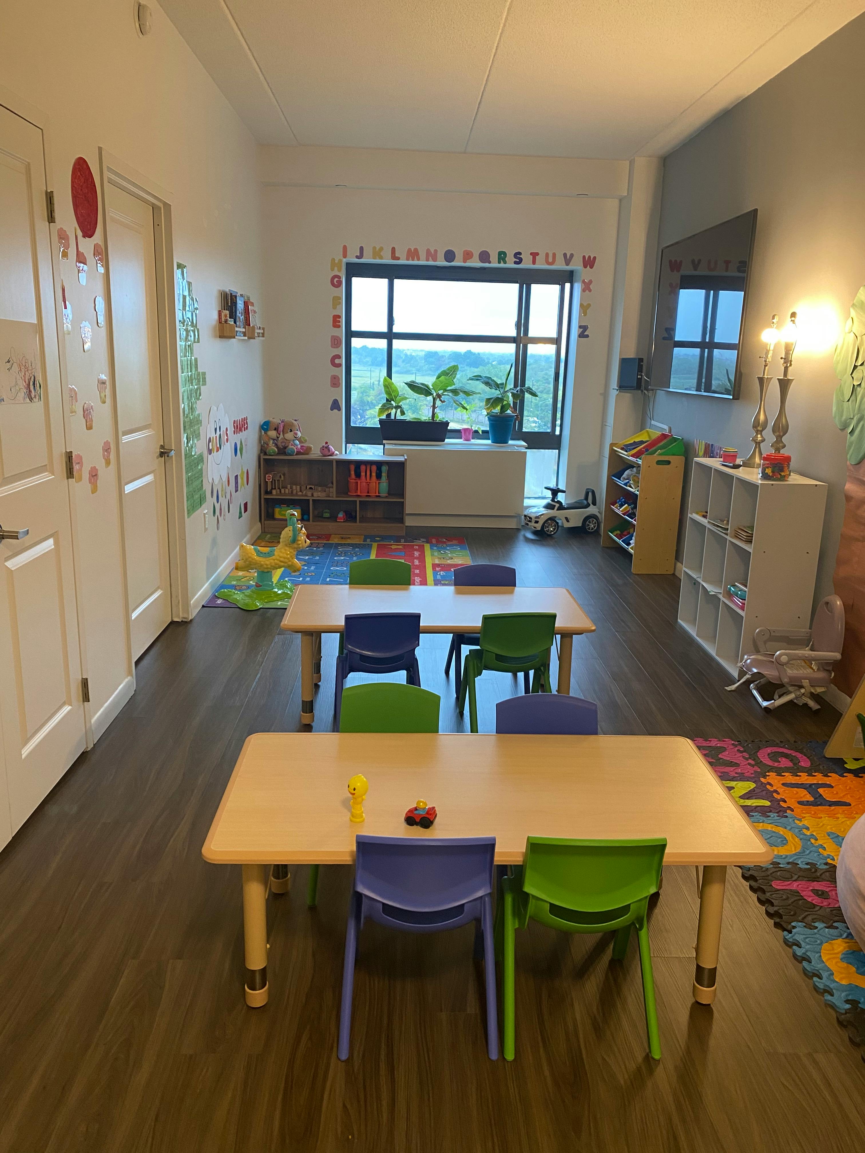 Classroom with small tables and chairs, alphabet on the wall