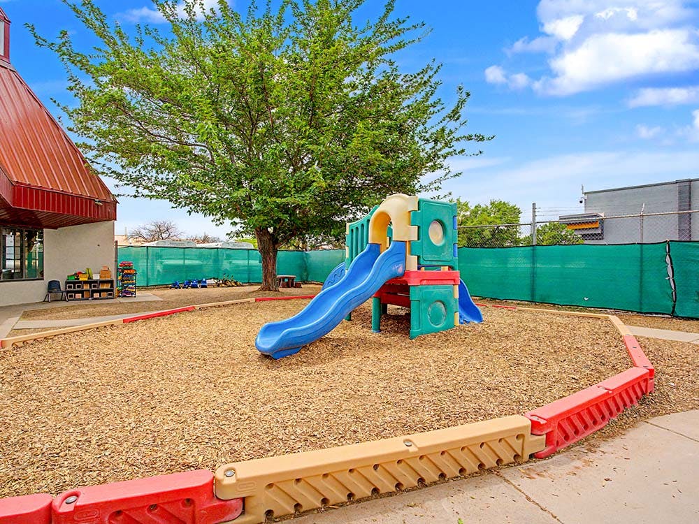 A colorful playground set with a blue slide on wood chips