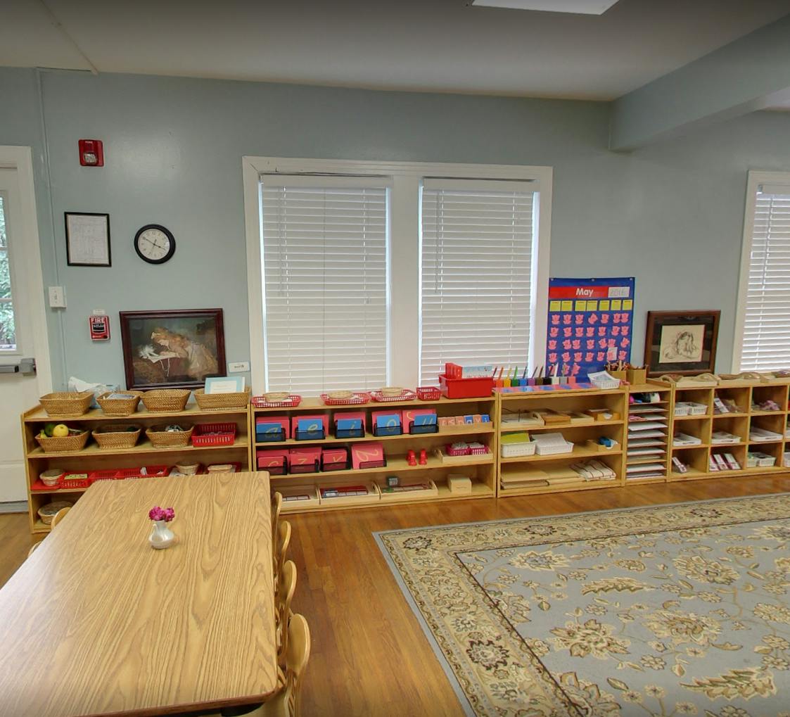 Classroom with wooden shelves filled with learning materials, a table, and a rug