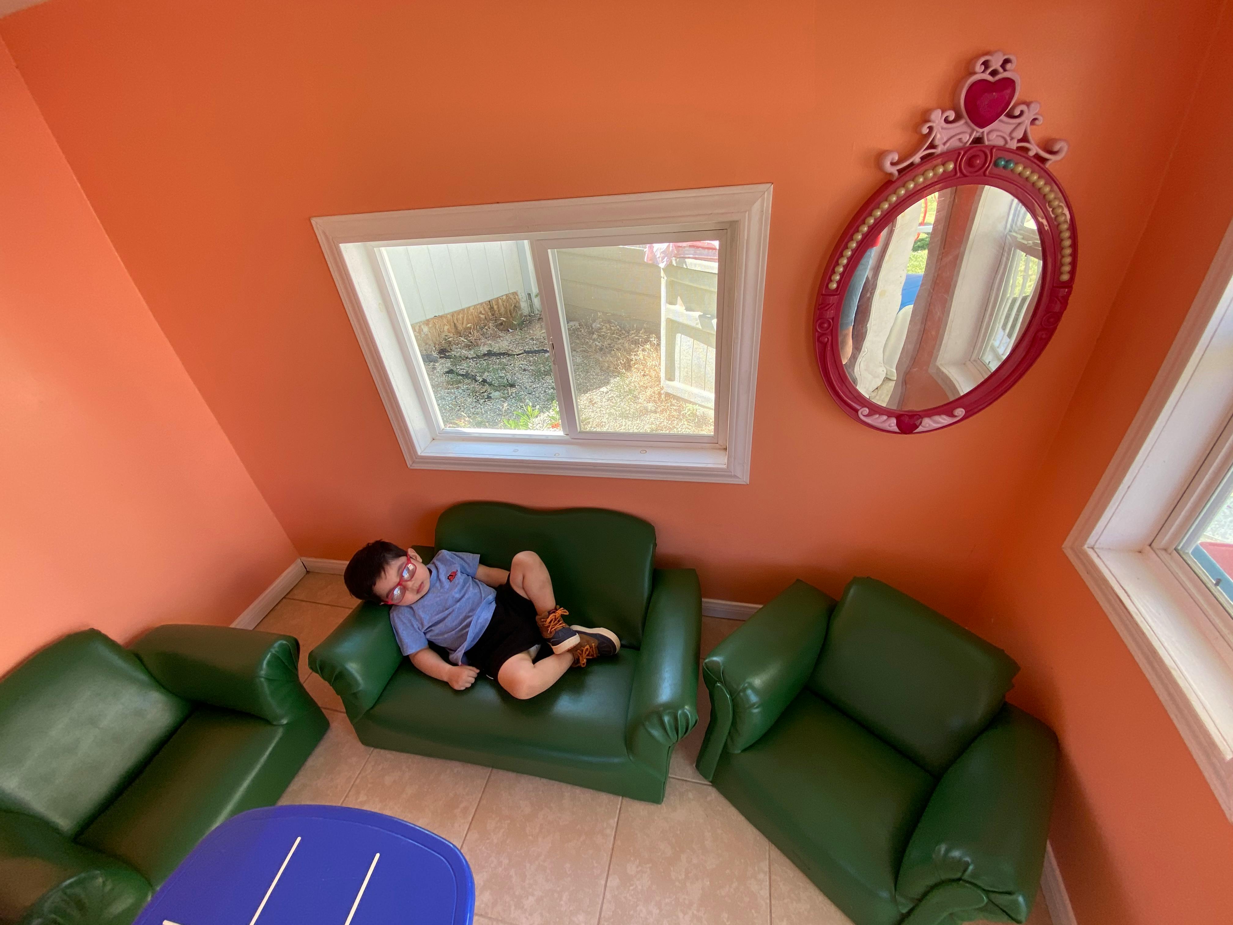 Child lying on a green armchair