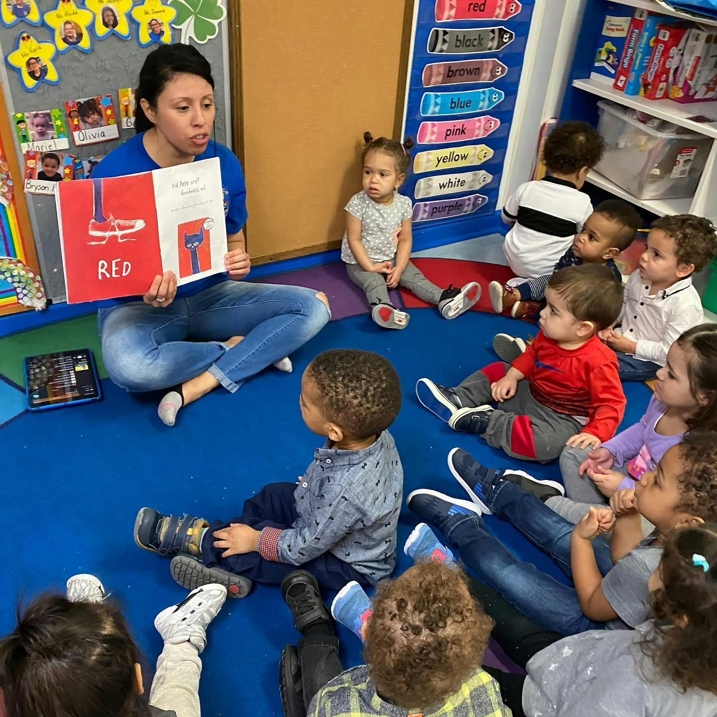 Person reading a book to a group of children sitting on the floor