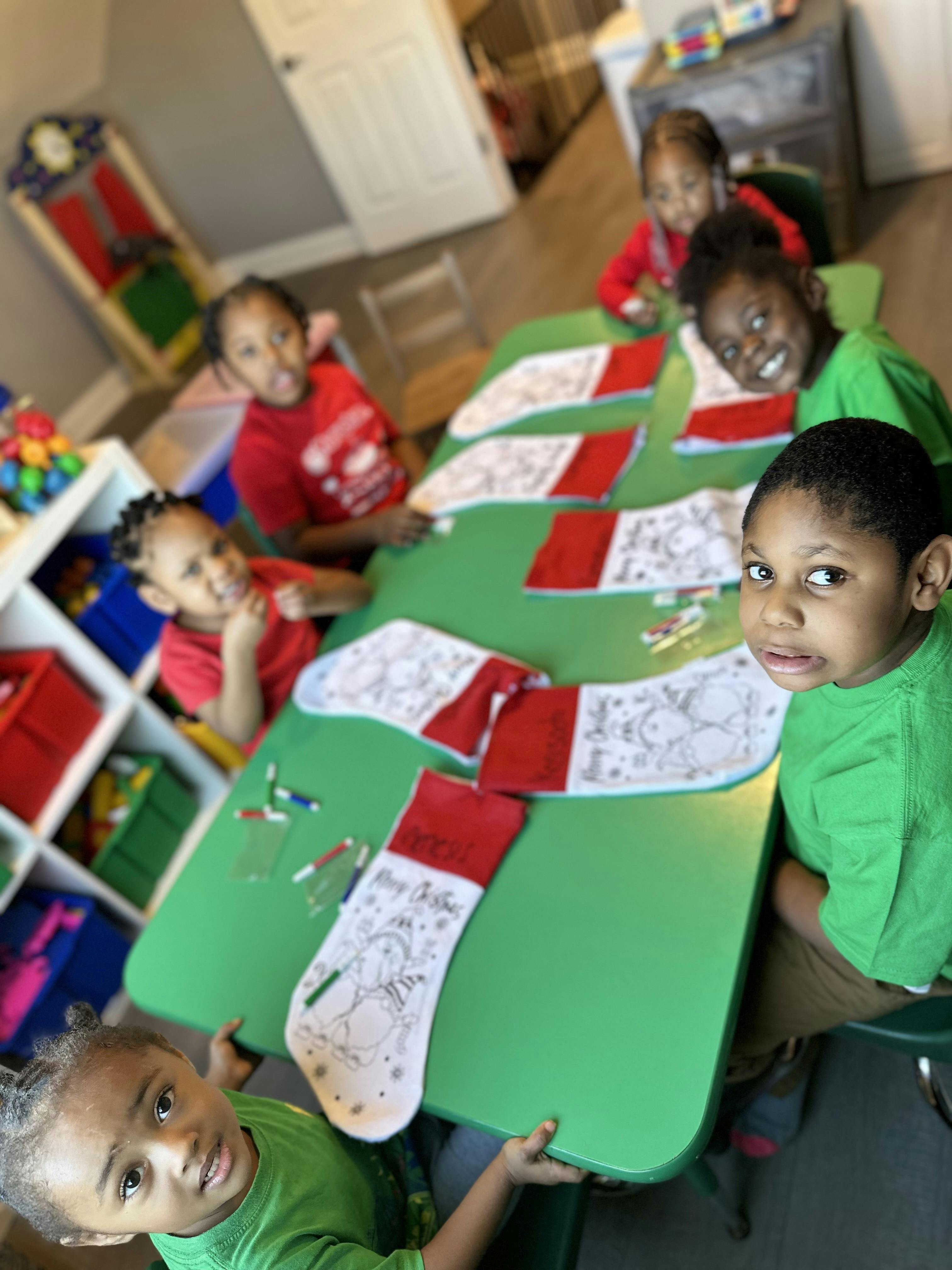 Children sitting at a green table with Christmas stockings for coloring