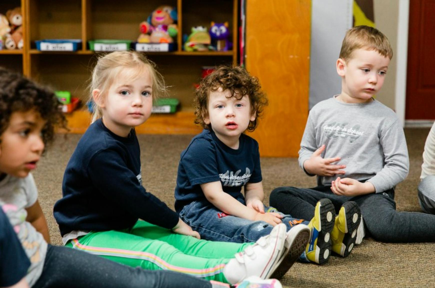 Three children sitting on the floor in a classroom