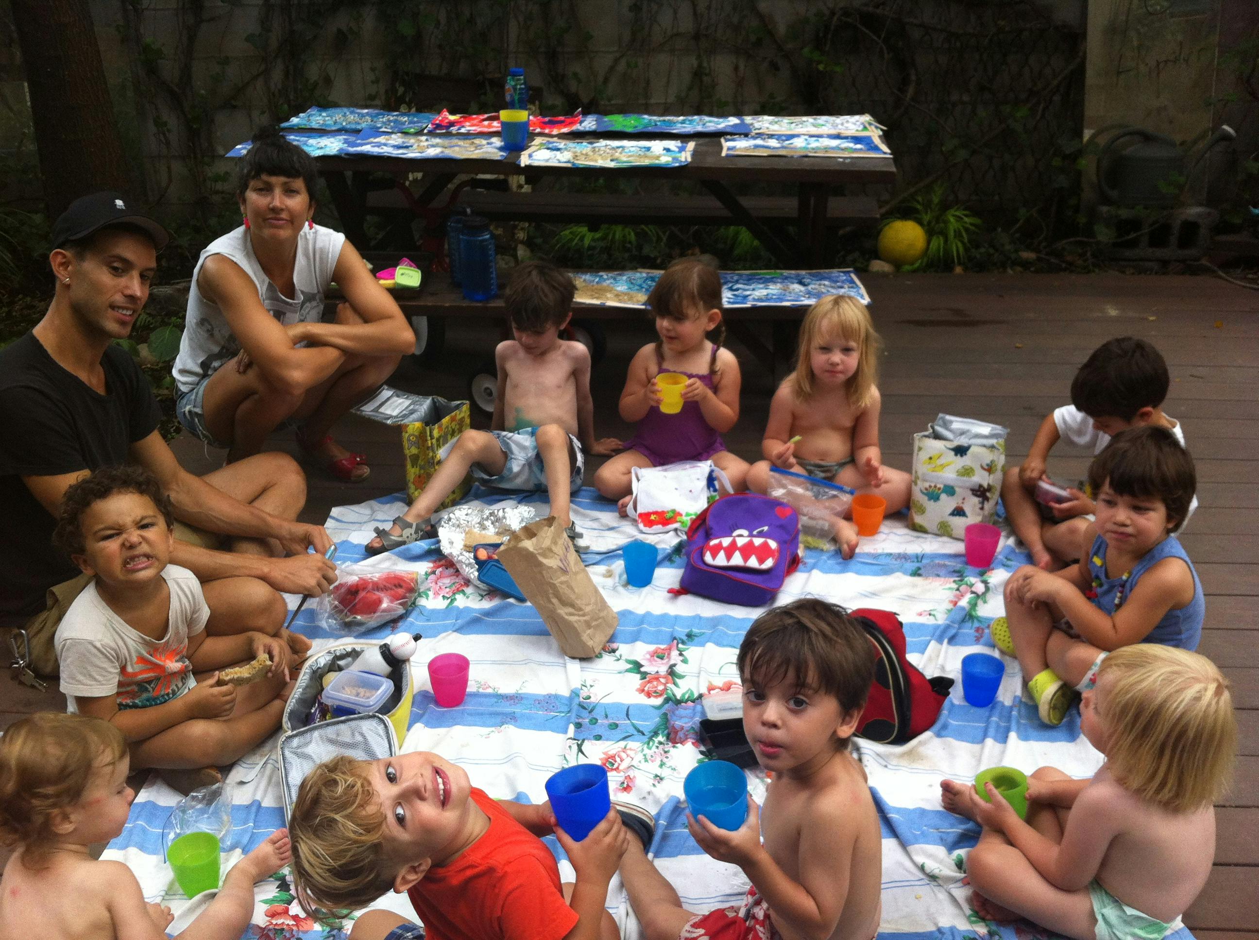 Adults and children sitting on a blanket outdoors