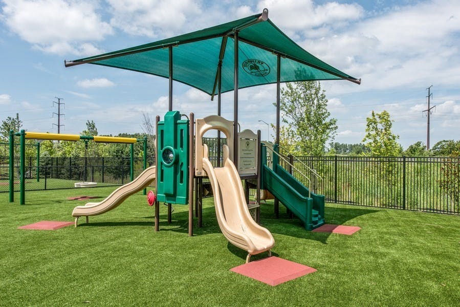 Playground with slides, swings, and a green shade canopy