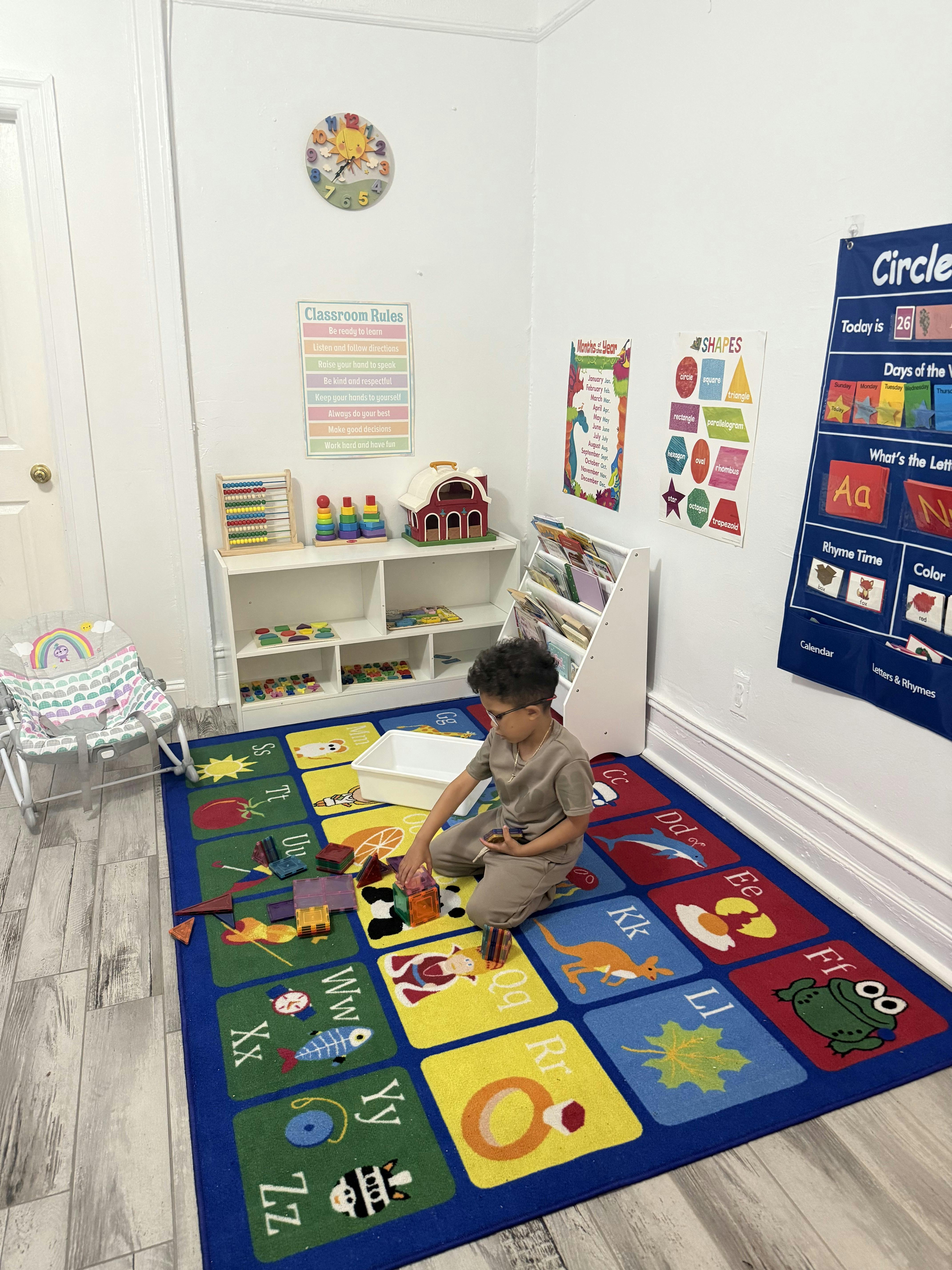 Child playing with colorful magnetic blocks on an alphabet rug in a classroom