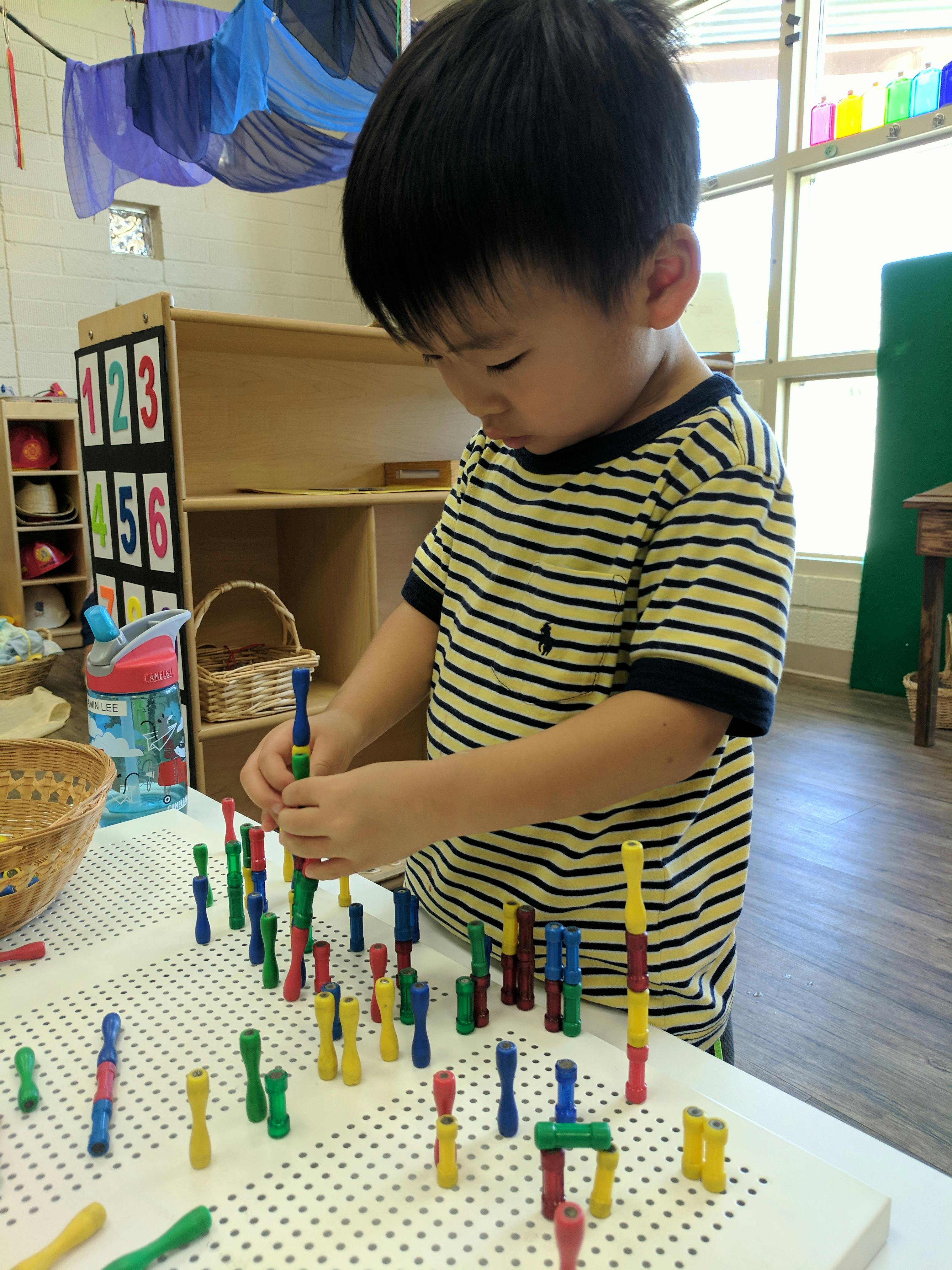 Child playing with colorful building blocks on a pegboard