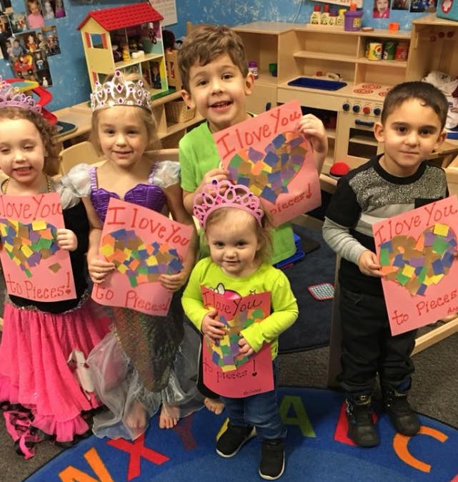 Five children holding up handmade cards that say "I love you"