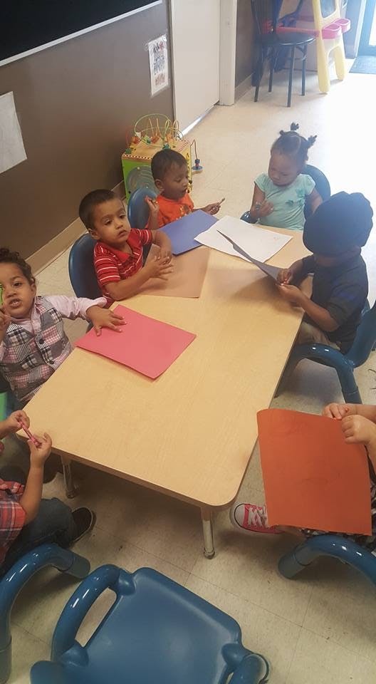Children sitting at a table with paper