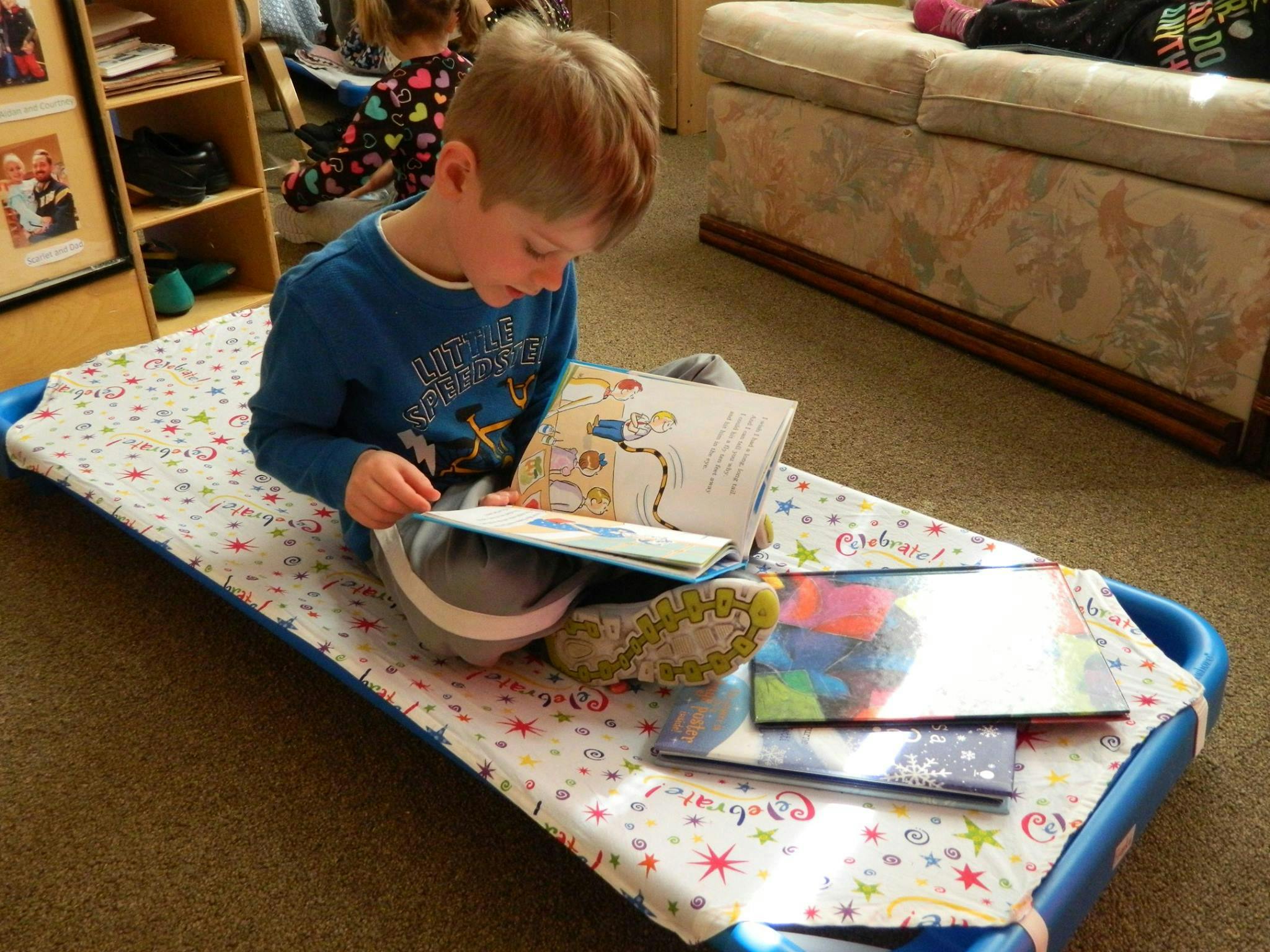 Child sitting on a cot reading a book