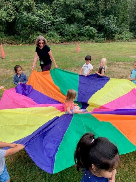 Adult and children playing with a colorful parachute outdoors