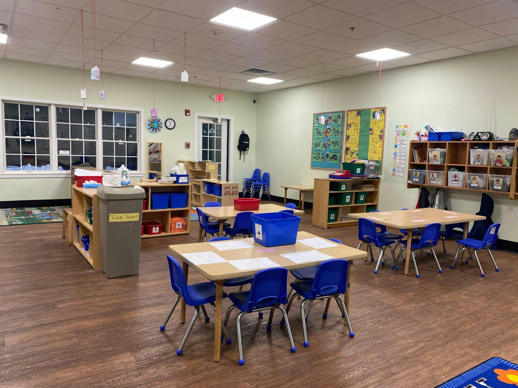 Empty classroom with small tables and chairs, shelves, and decorations