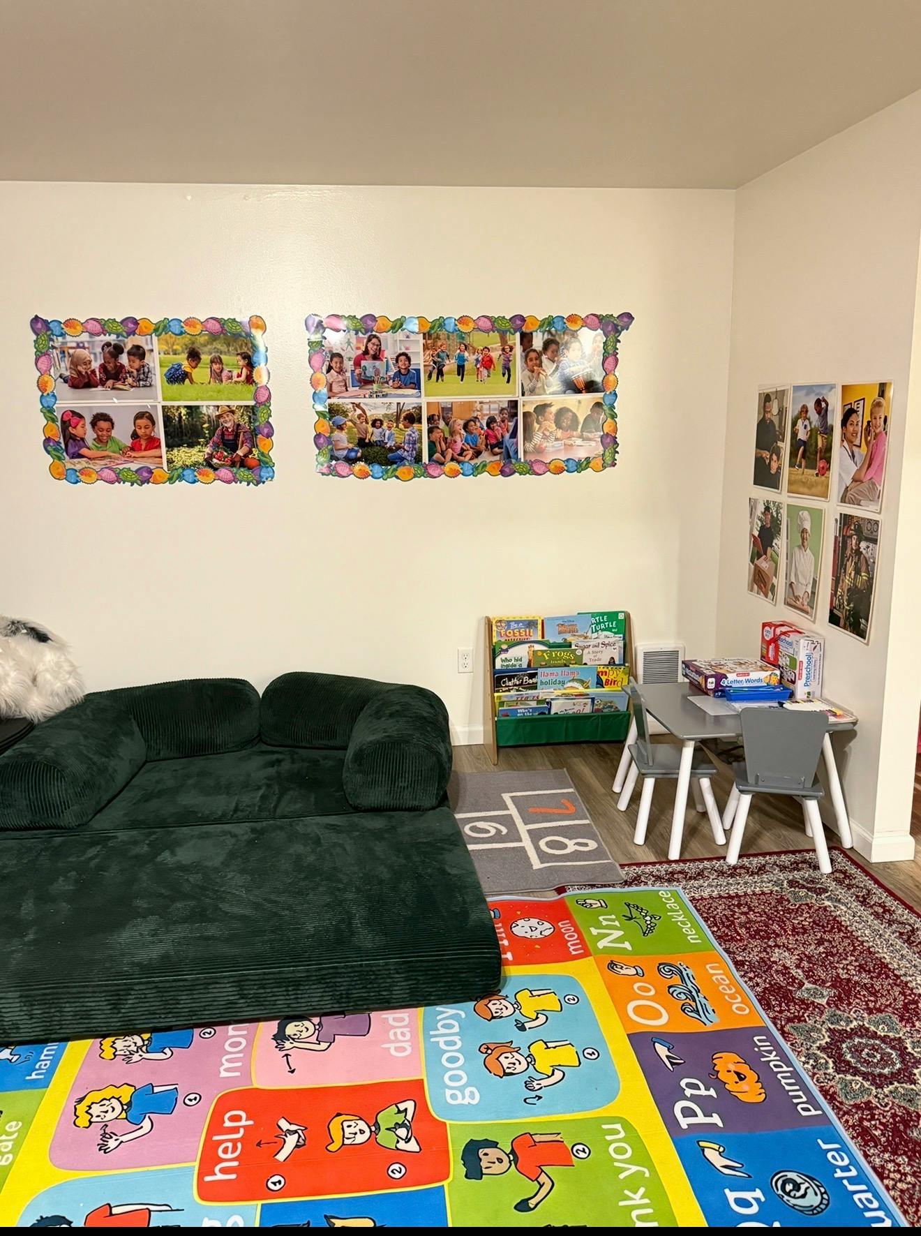 Children's playroom with a green sofa, bookshelf, small table with chairs, and colorful rug