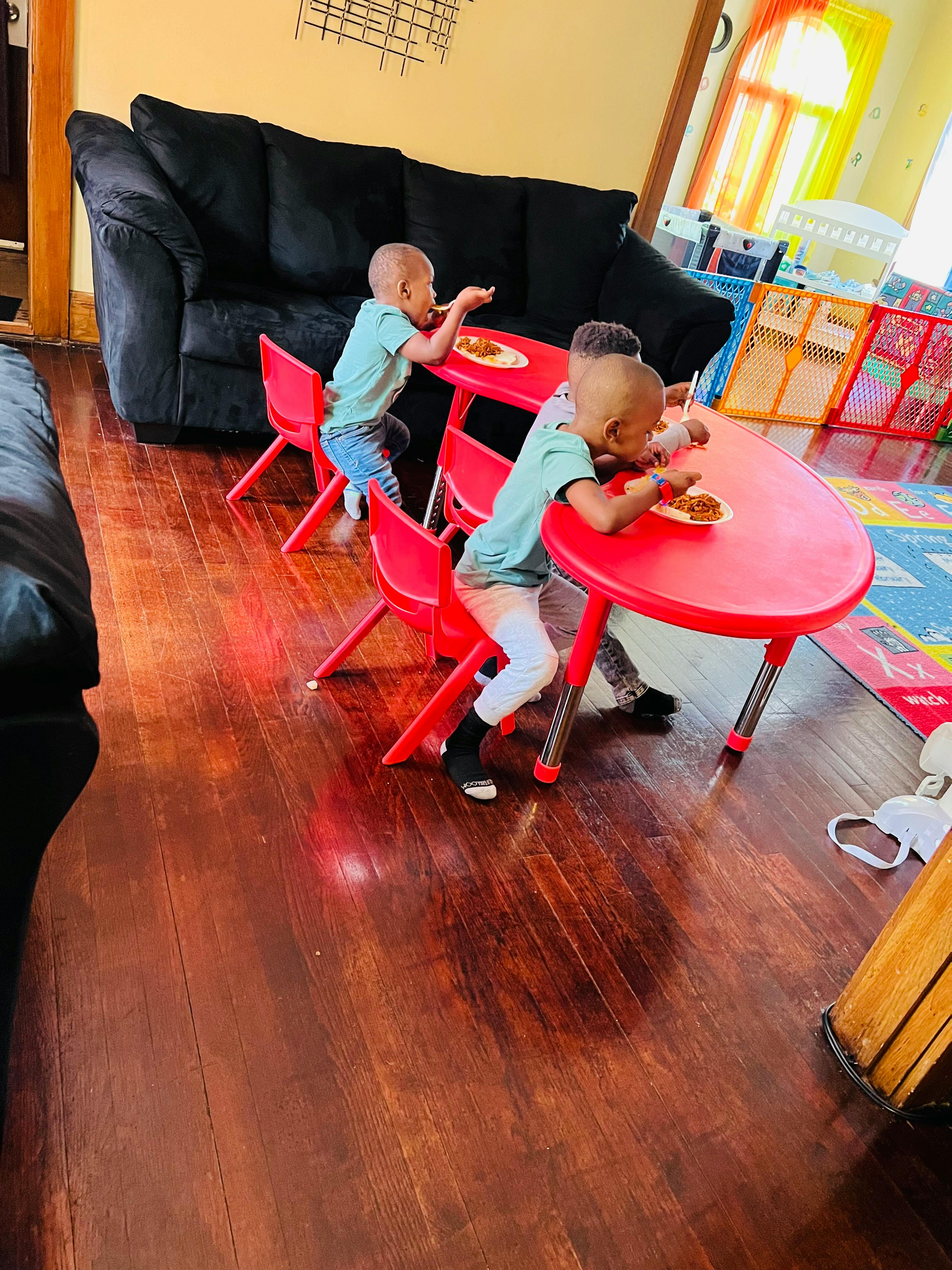 Three children eating at red tables