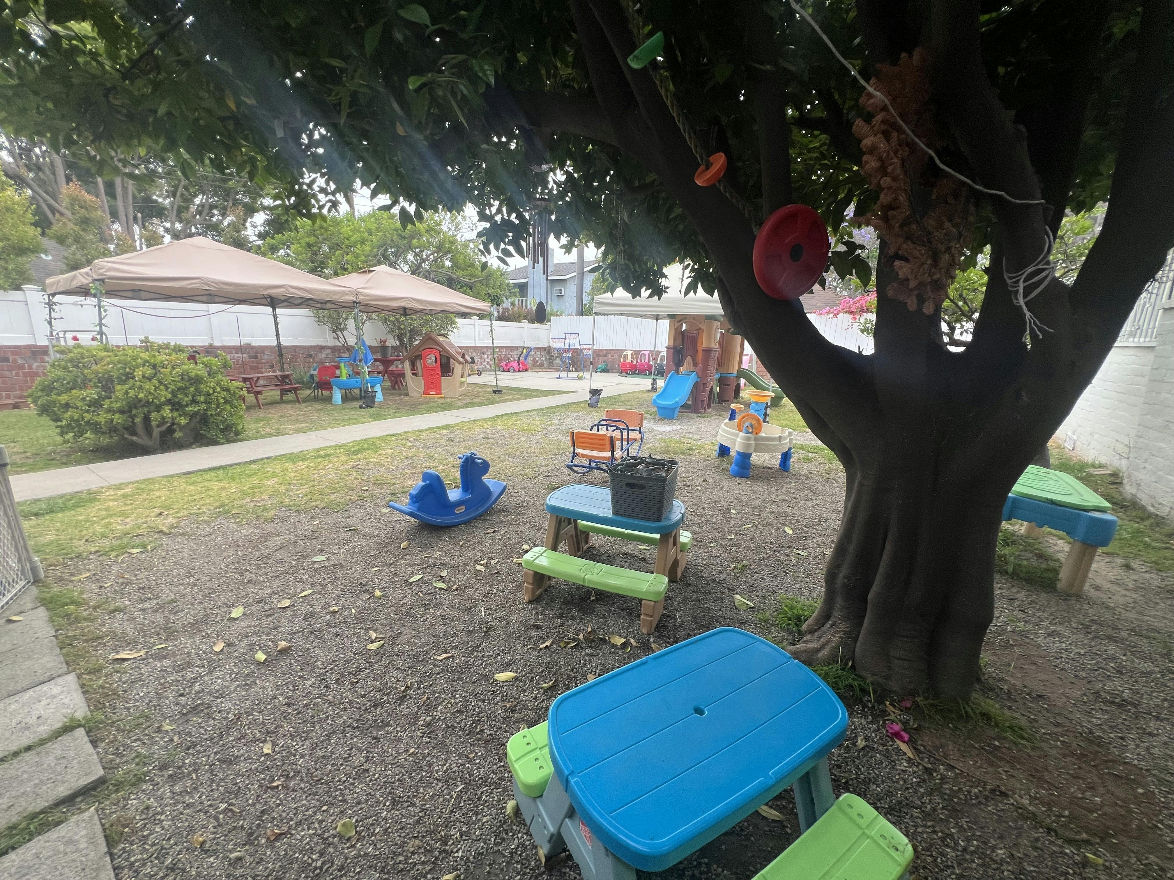 Outdoor playground with small tables, chairs, and play equipment