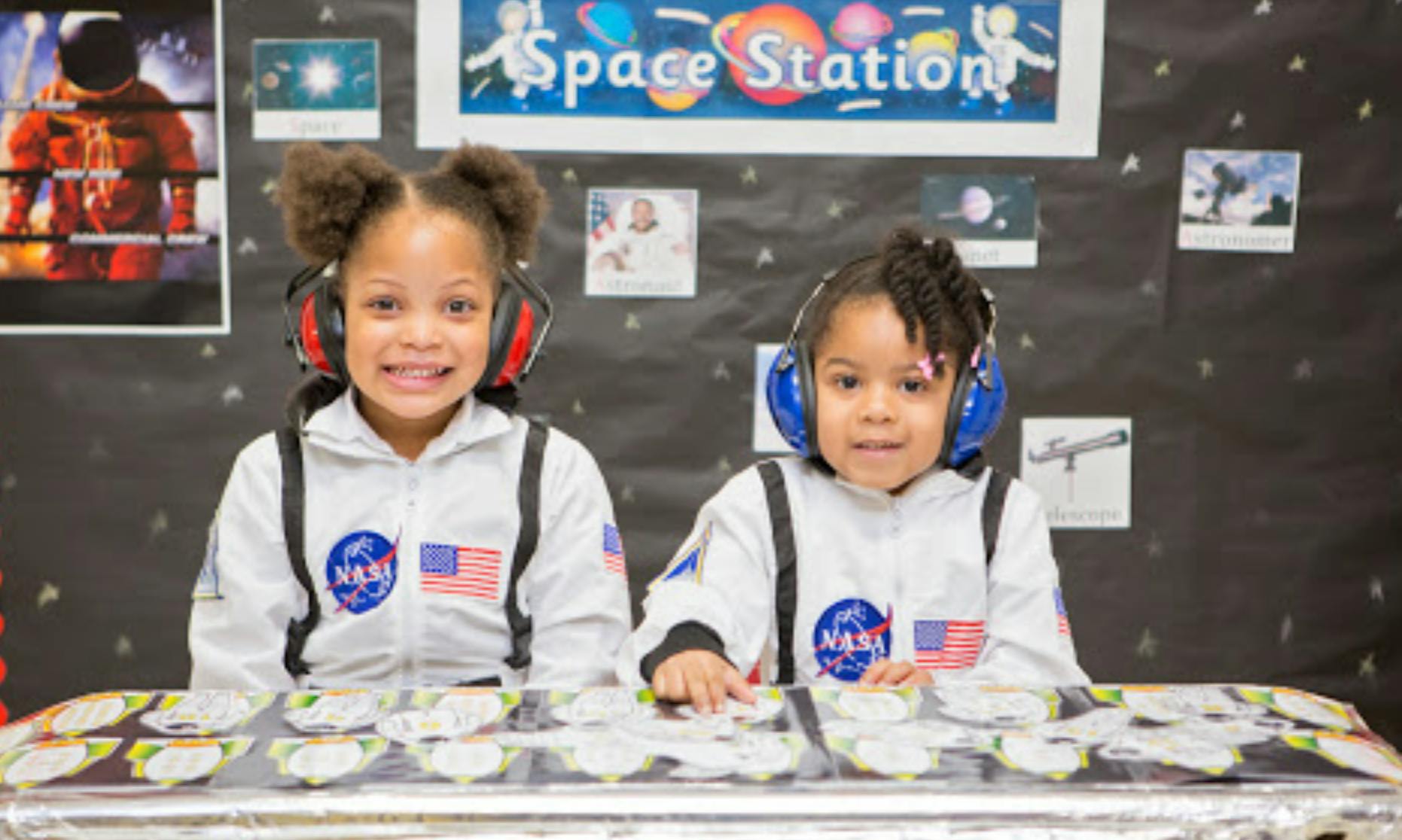 Two children in astronaut suits wearing headphones