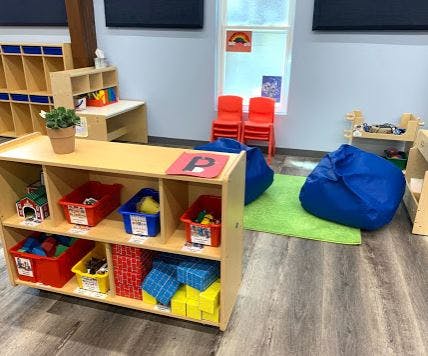 Classroom with wooden shelves, red chairs, and blue bean bags