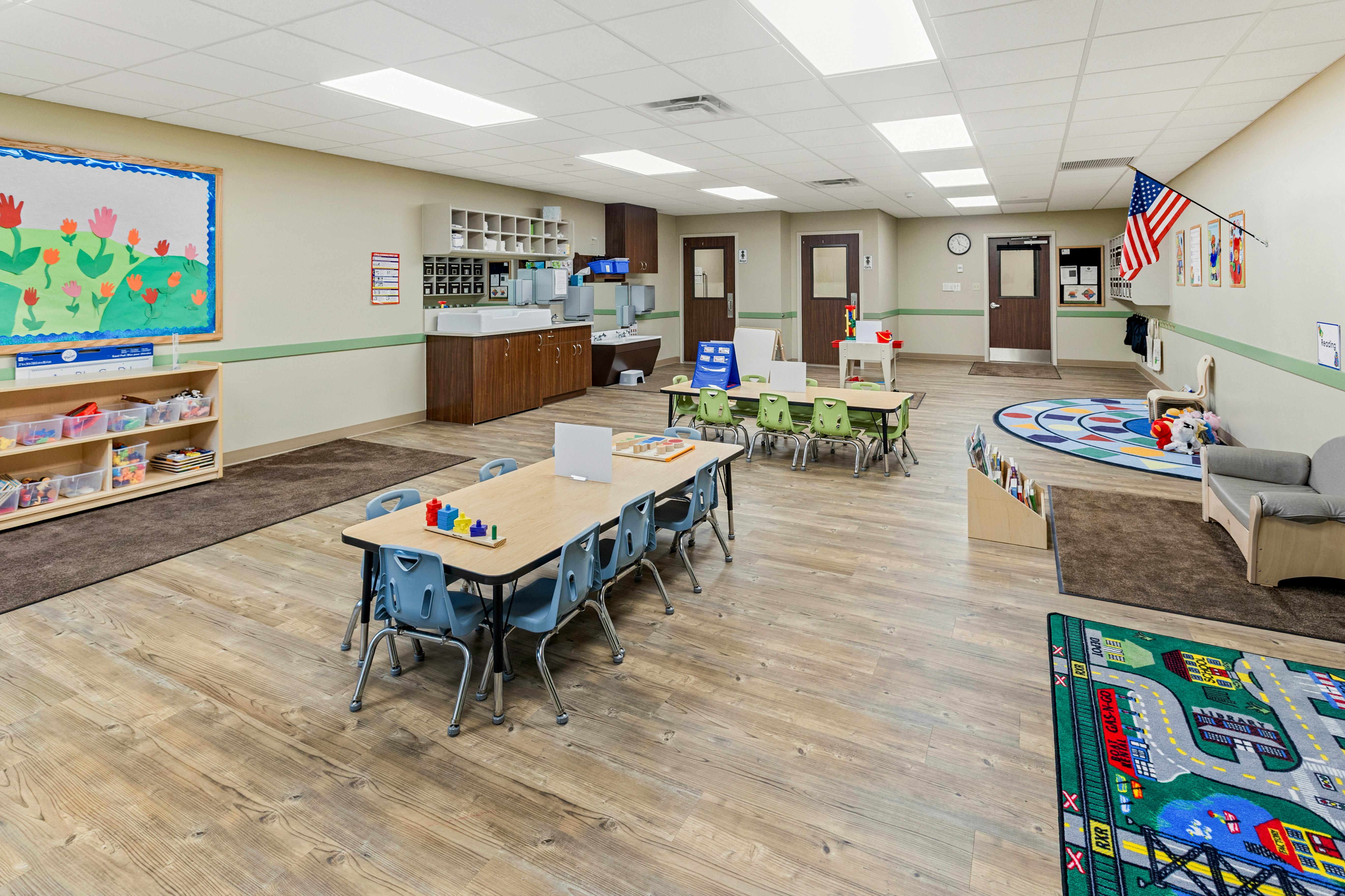 Classroom with tables, chairs, changing station, cubbies, and play areas
