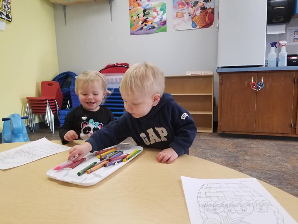 Two children at a table with crayons and crayons