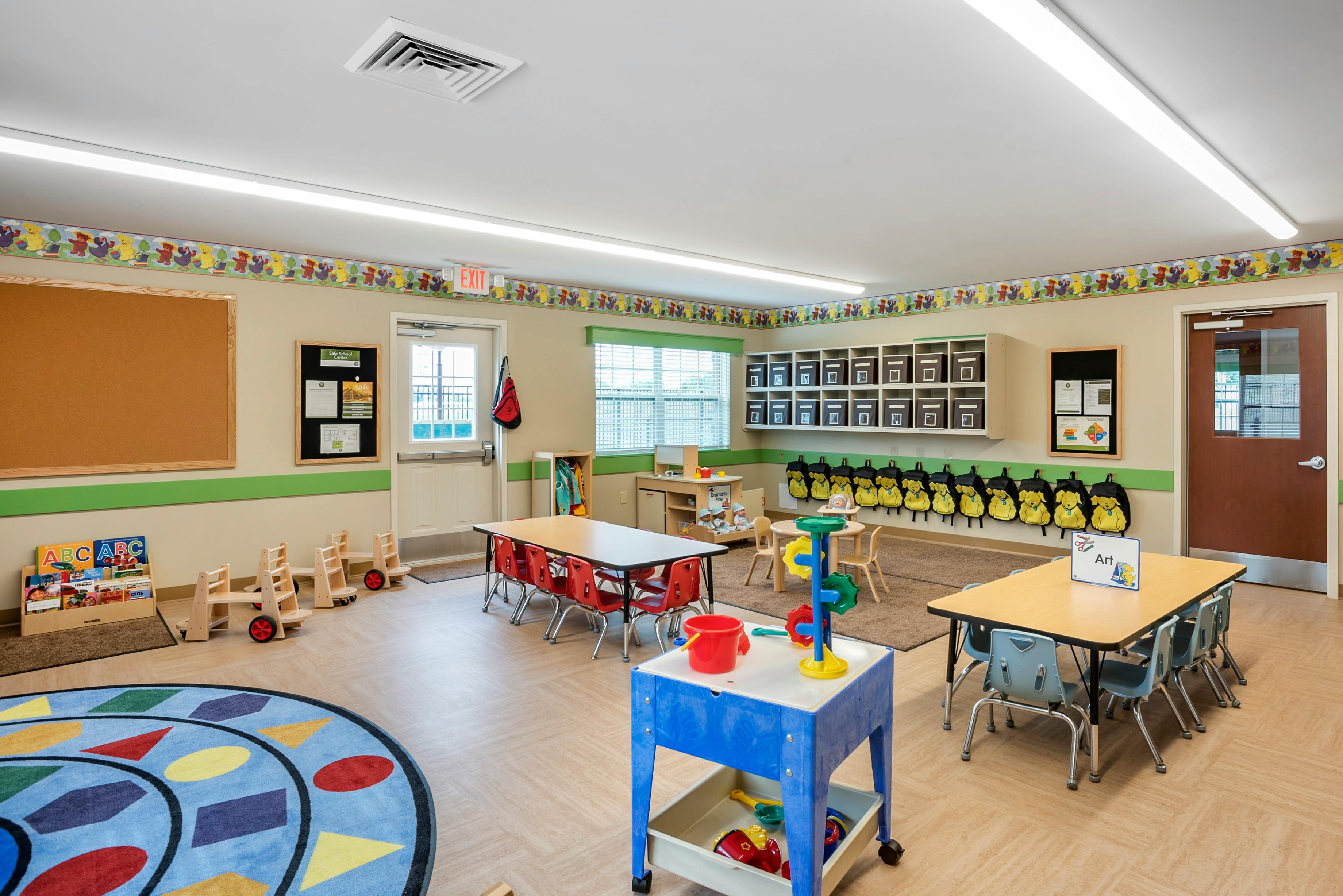 Empty classroom with small tables and chairs, toys, and learning materials