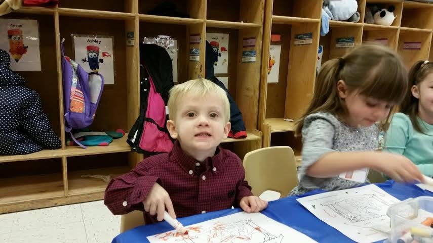 Child coloring at a table in a classroom