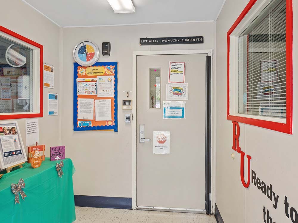 A hallway with a bulletin board, an entrance door, and a table with decorations