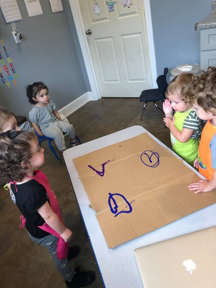 Children gathered around a table with a cardboard box