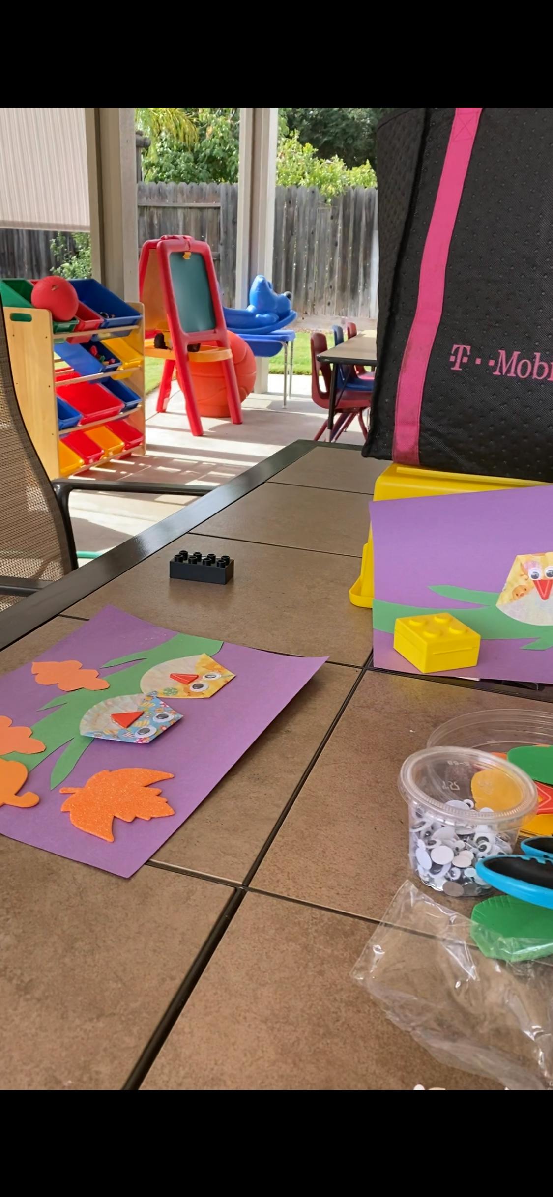 Craft supplies and finished crafts on a table with play equipment in the background