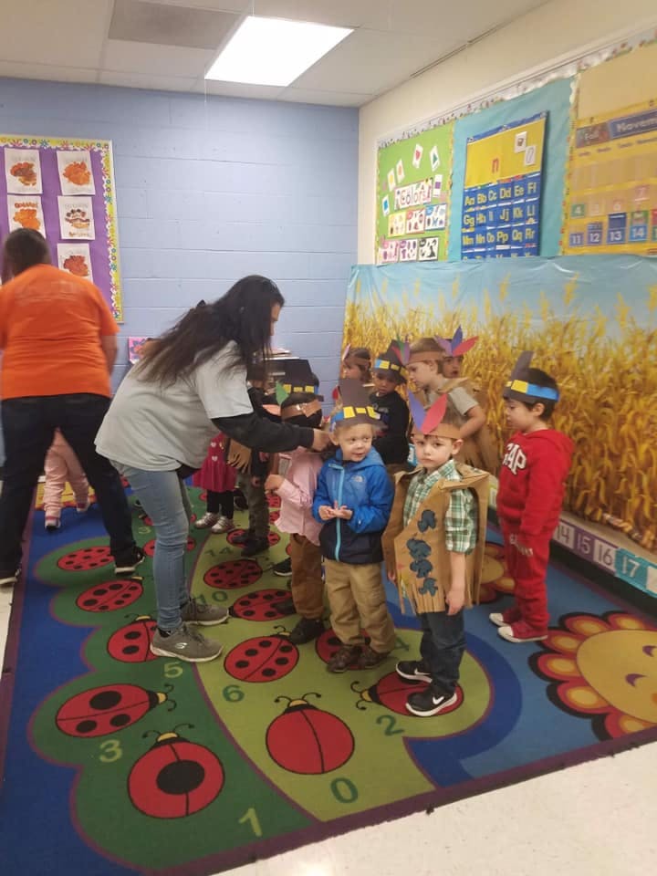 Adults interacting with children in costumes in a classroom