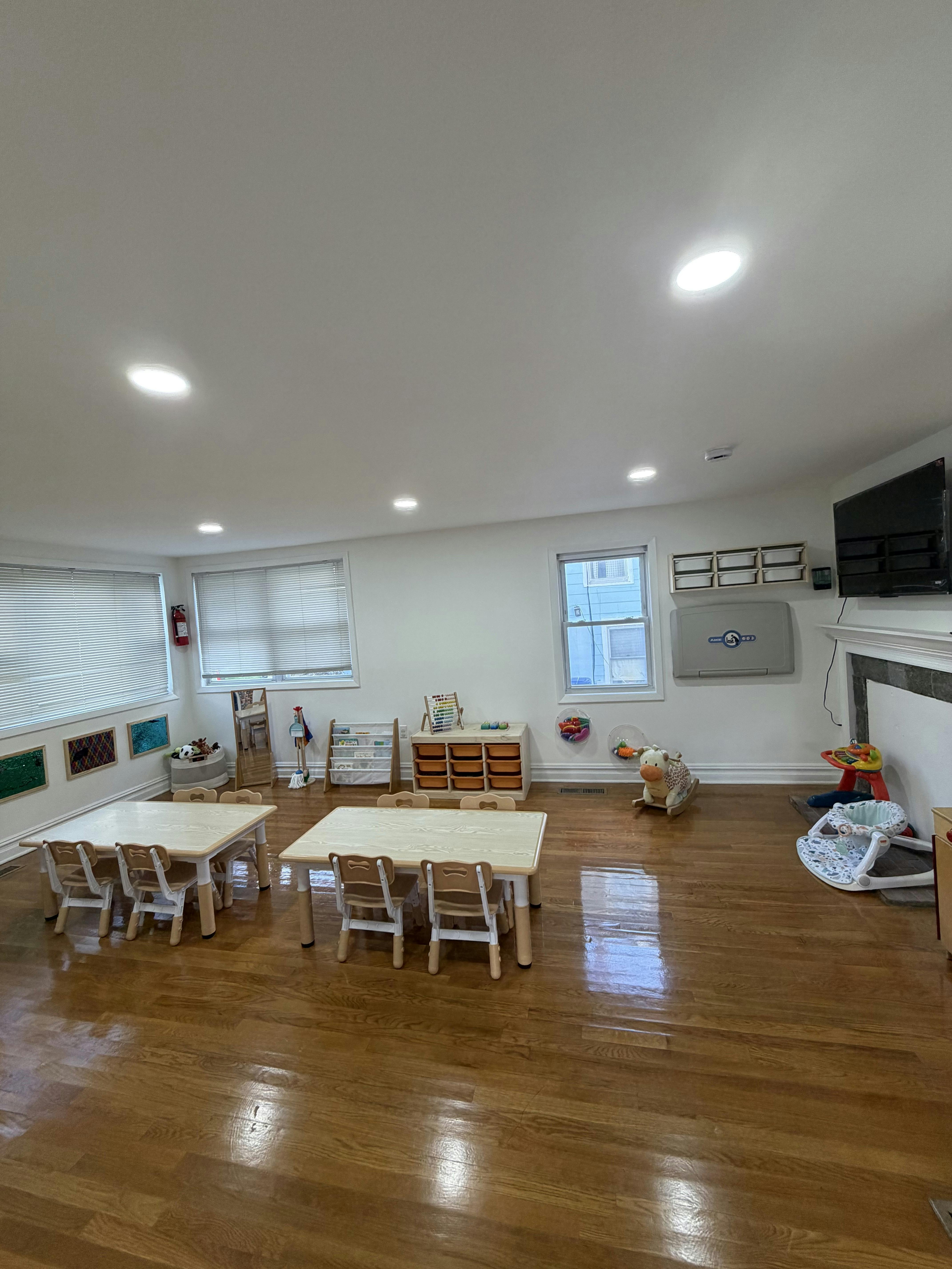 Classroom with small tables, chairs, and toys, with bright overhead lights