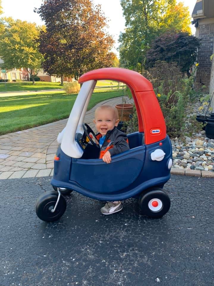 Child in a toy car on a driveway