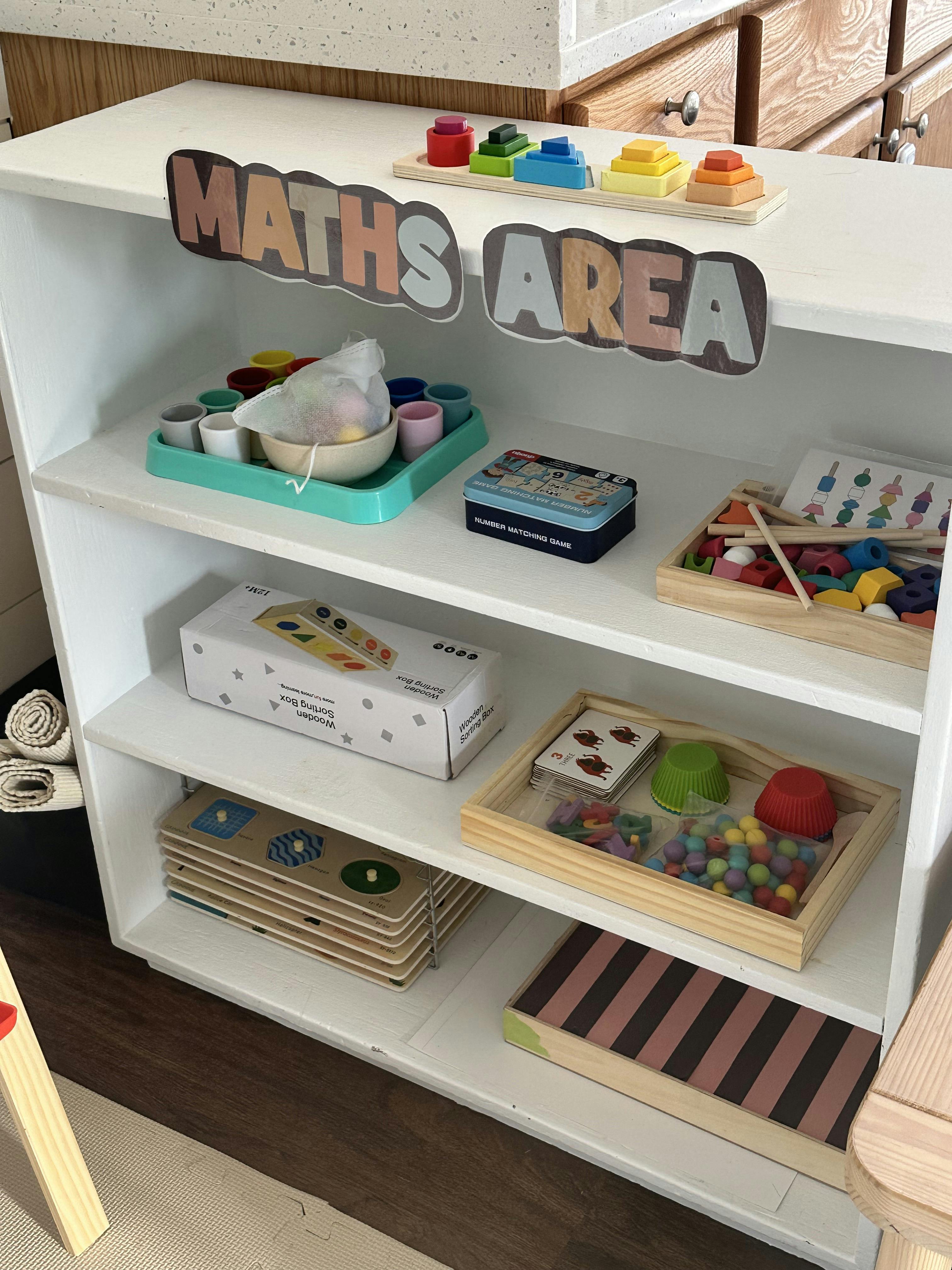 Shelf with a "Maths Area" sign, holding colorful educational toys and games