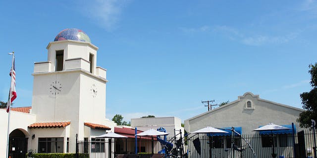 Building with a clock tower and dome, next to a playground