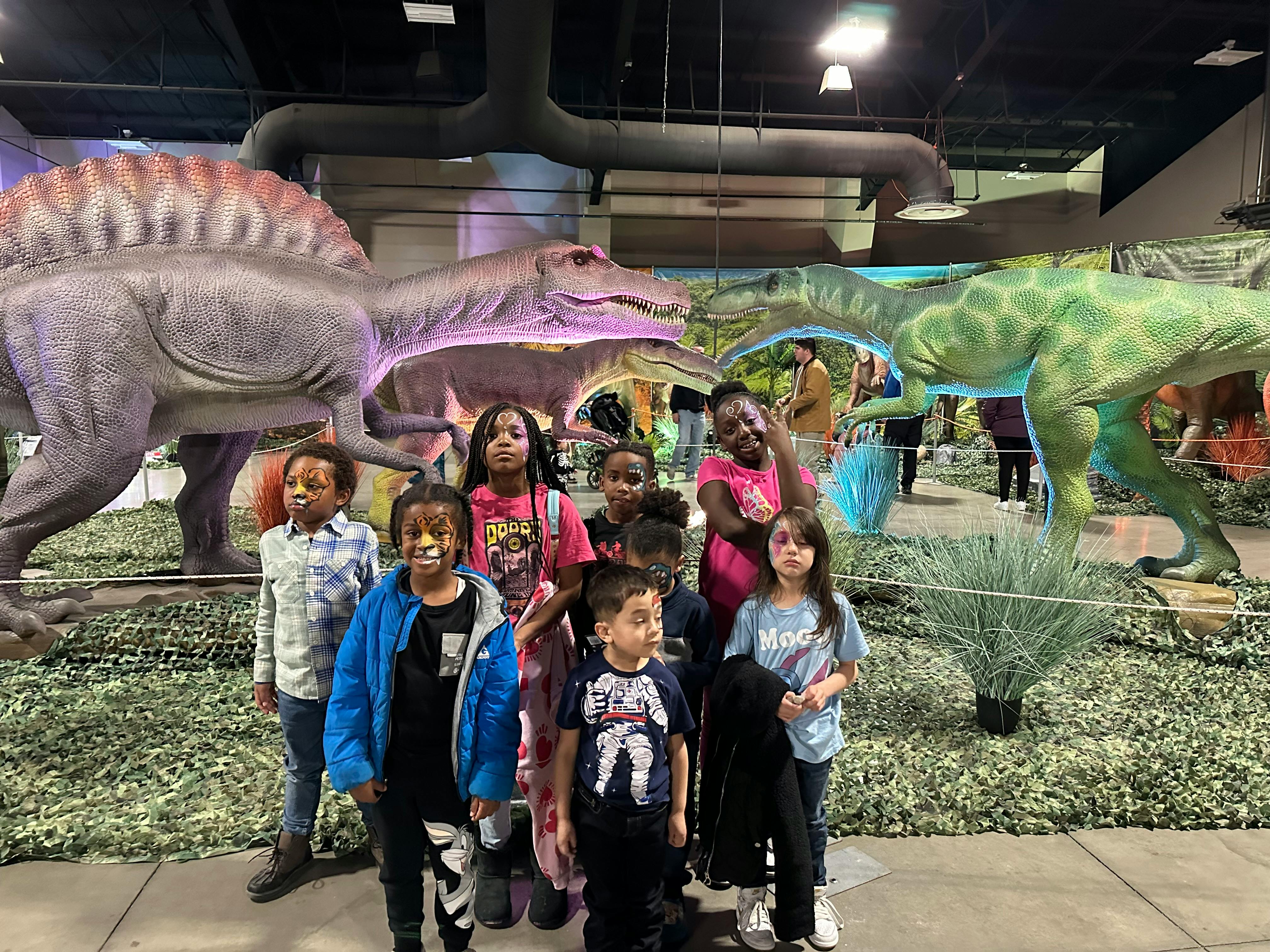 Group of children standing in front of dinosaur models