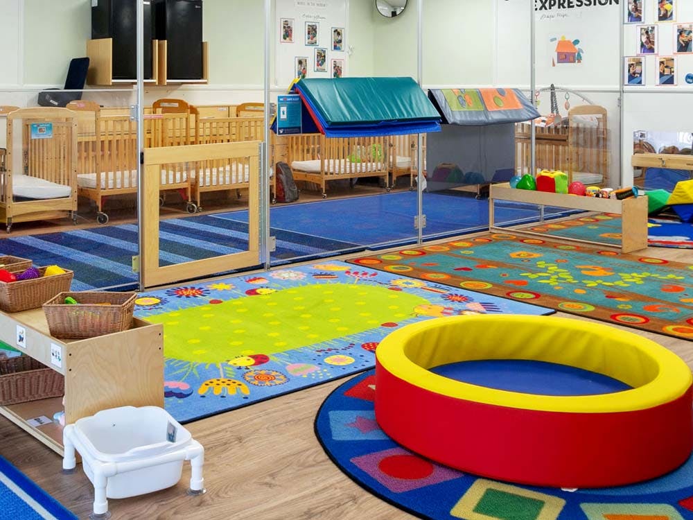 Cribs and play mats in a bright daycare classroom