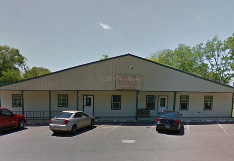 Building with a sign that reads "Happy Days" and cars parked in front