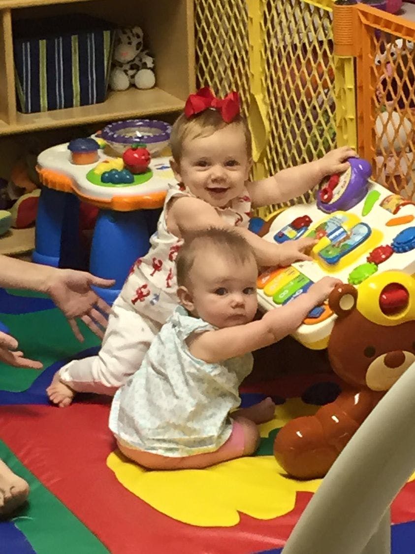 Two children playing with toys on a colorful mat