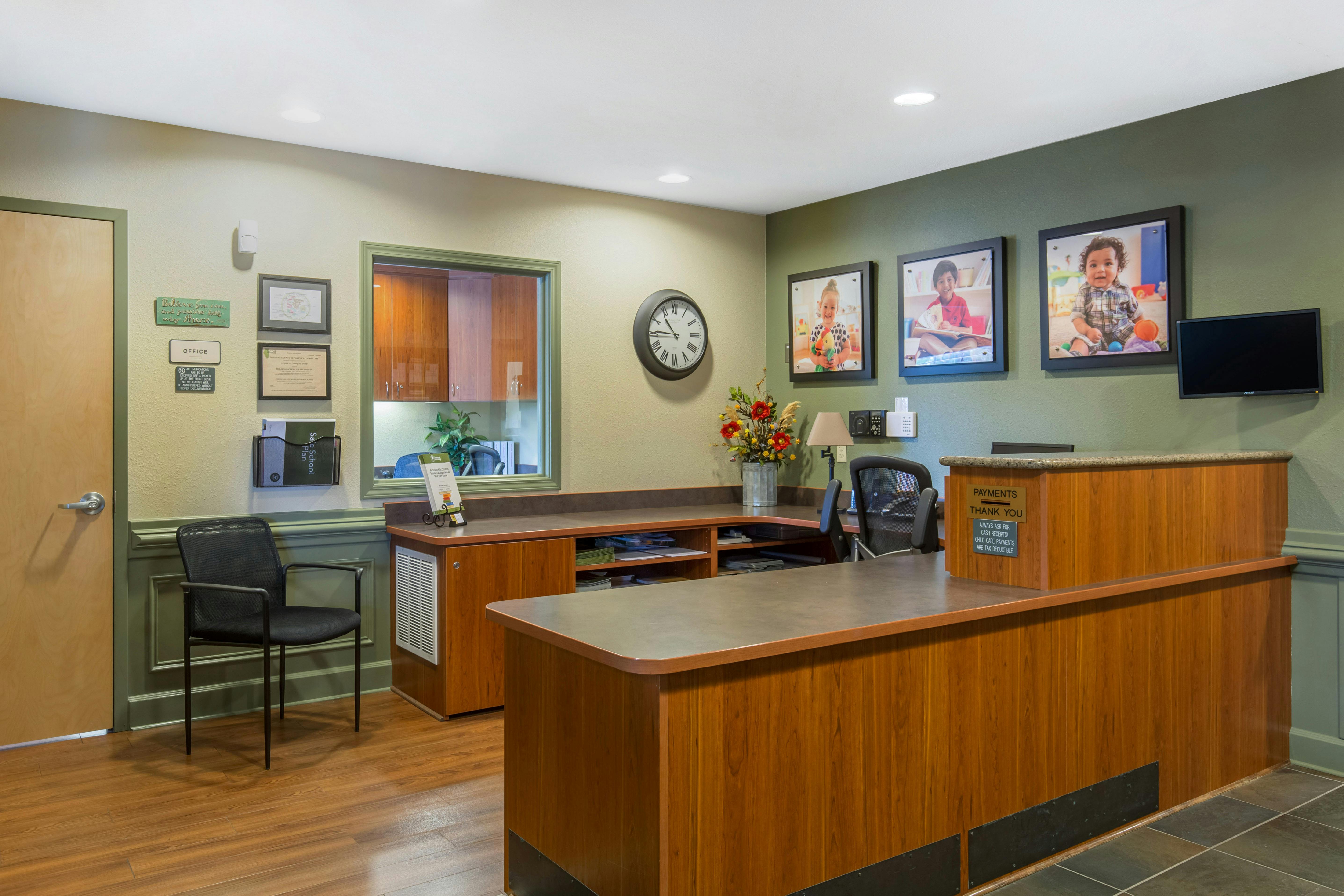 Reception desk with office door, window, wall decor, and framed child photos