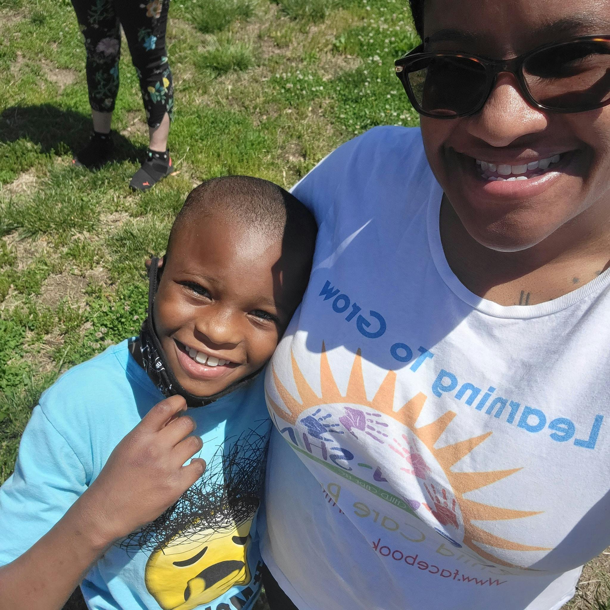 Smiling person wearing sunglasses and child in blue shirt