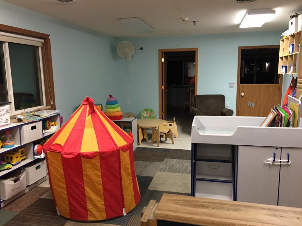 Playroom with a red and yellow striped tent, shelves, and changing table