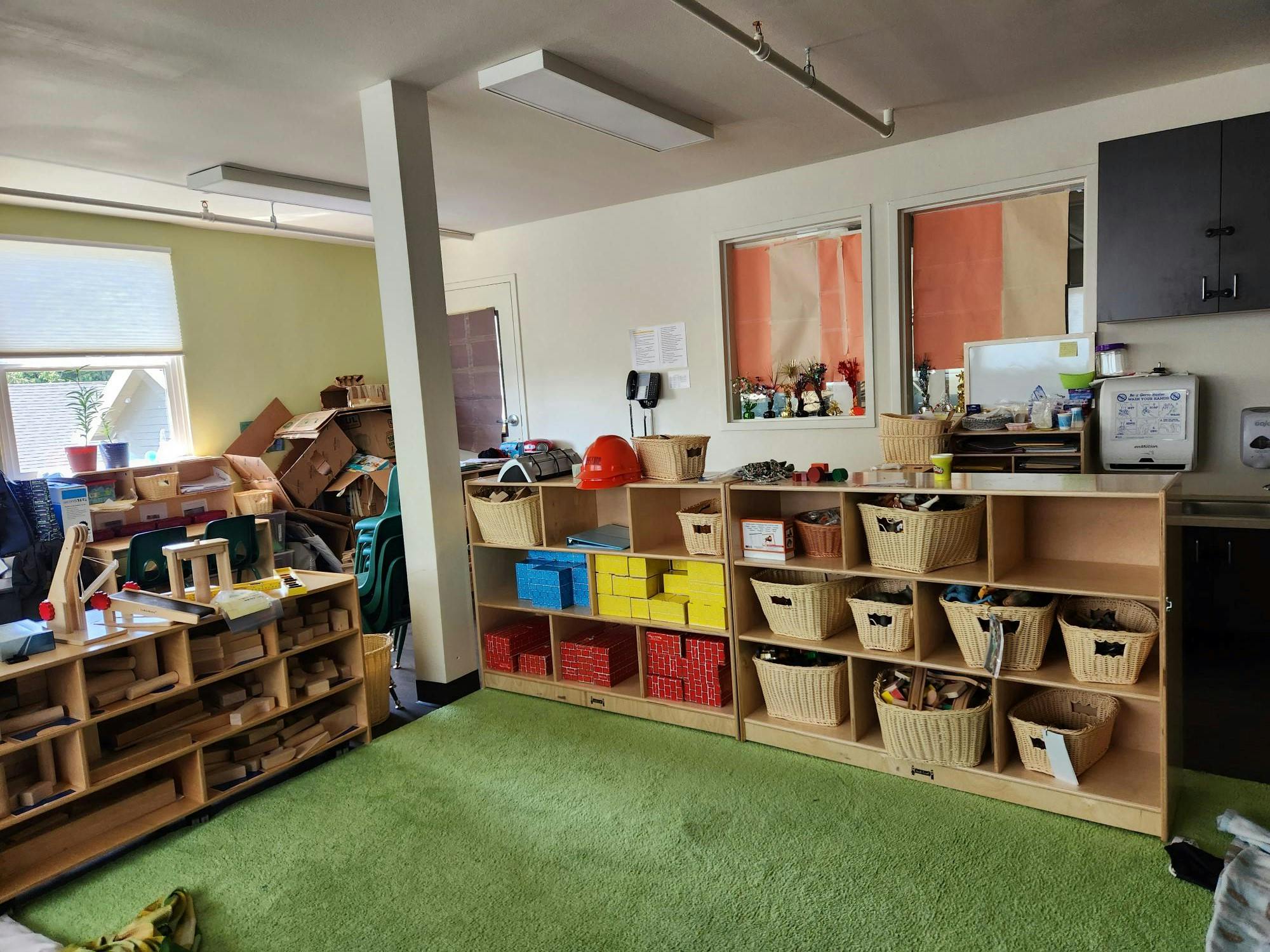 Classroom with shelves of baskets and bins, green carpet