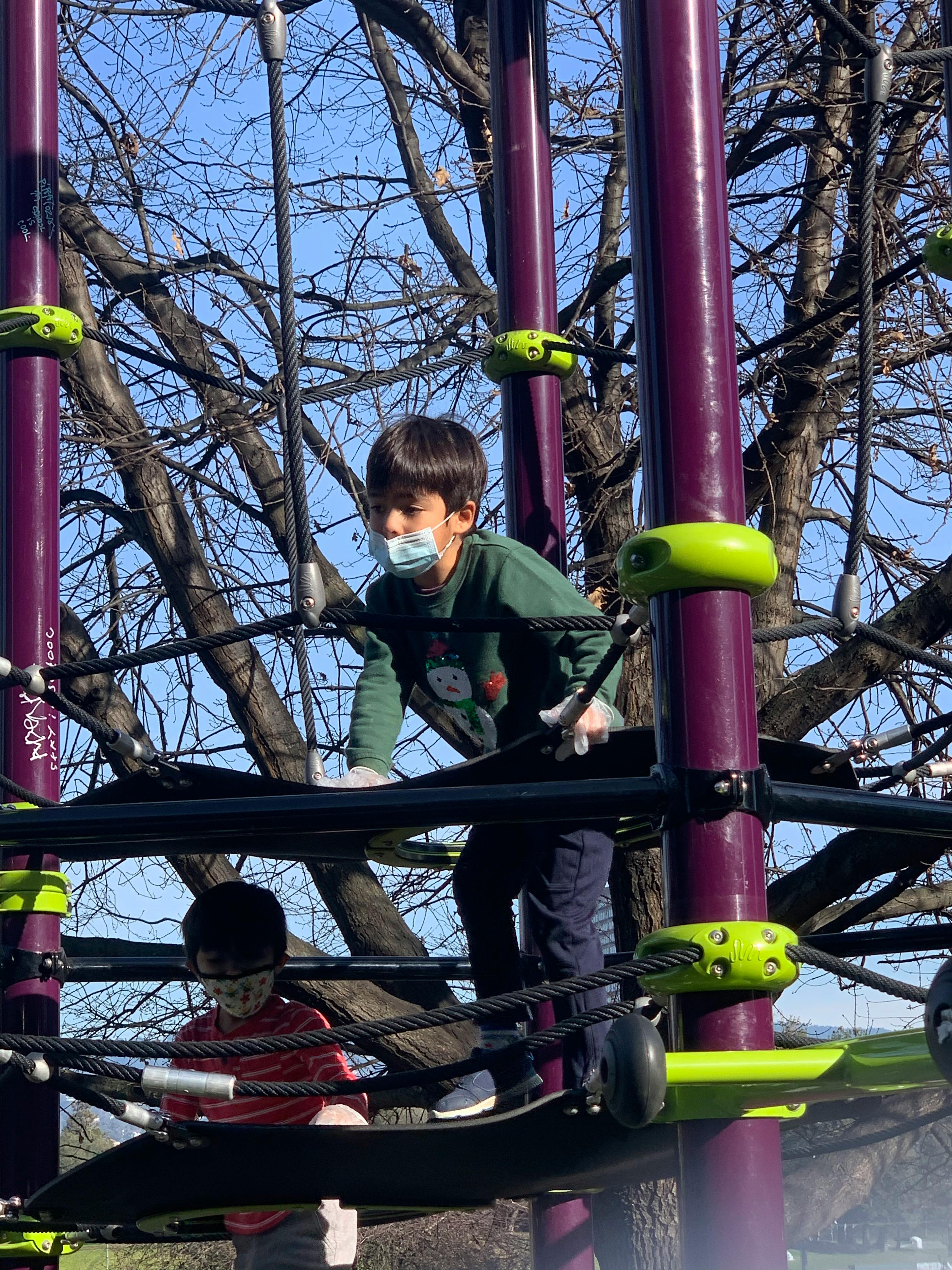 Two children on a rope climbing structure at a playground